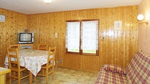 A room with wooden panel walls, a dining table with chairs, a television, and a sofa. - Wifi, Ground floor, tv, 25m², Les Gets (Les Gets)