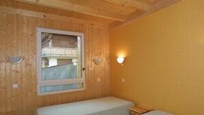 A room with wooden walls and a large window. There are two beds with white bedding. - Wifi, Ground floor, terrace, tv, 58m², Les Gets (Les Gets)