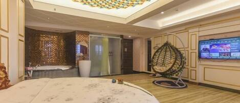 A hotel room with a large bed, a hanging chair, a TV, and a decorative ceiling.