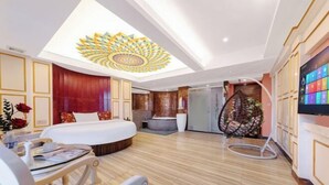 A hotel room with a large bed, a desk with a chair, a TV, a ceiling light fixture, and a wall-mounted TV. - Xinyue Theme Hotel (Longjiang Convention and Exhibition Center Shop) (Foshan)