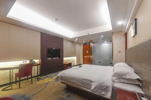 Habitación de hotel con cama, escritorio, silla y televisor.