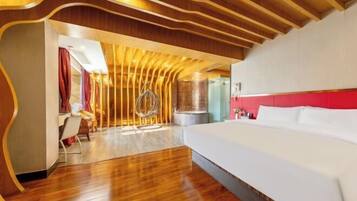 A modern hotel room with a wooden ceiling, a large bed, and a dining area with a chair and table.