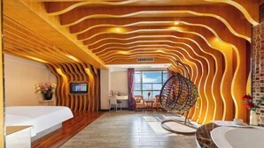 A hotel room with a wooden ceiling, a large window, a bed, a desk, and a chair. - Xinyue Theme Hotel (Longjiang Convention and Exhibition Center Shop) (Foshan)