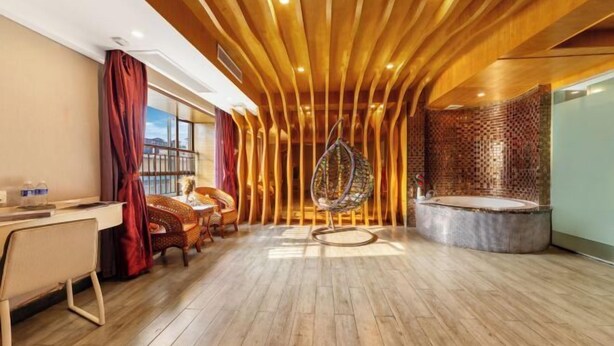 A modern room with a wooden ceiling, a hanging chair, a round bathtub, and a desk with chairs. - Xinyue Theme Hotel (Longjiang Convention and Exhibition Center Shop) (Foshan)