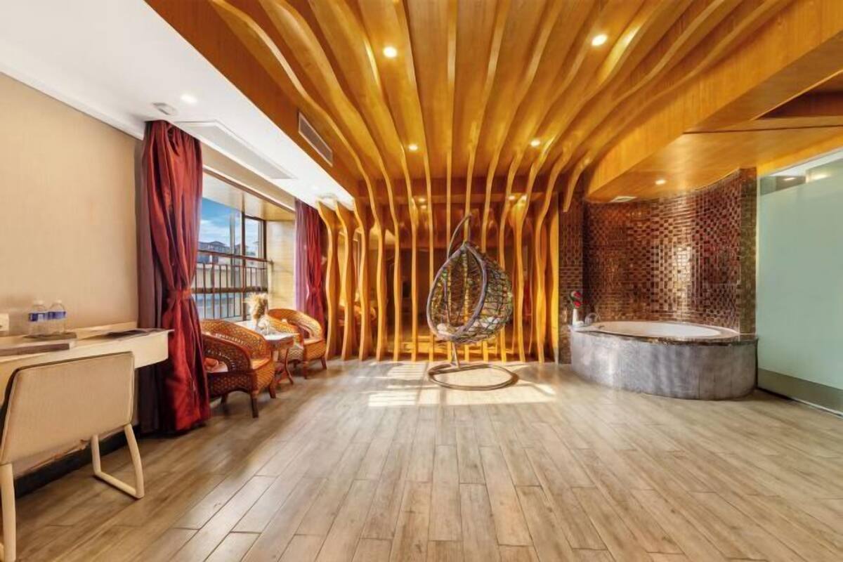 A modern room with a wooden ceiling, a hanging chair, a round bathtub, and a desk with chairs.