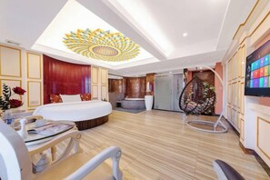 A modern hotel room with a large bed, a dining area, a seating area, and a TV on the wall. - Xinyue Theme Hotel (Longjiang Convention and Exhibition Center Shop) (Foshan)