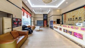 A hotel lobby with a reception desk, leather sofas, a chandelier, and a wall with promotional posters. - Xinyue Theme Hotel (Longjiang Convention and Exhibition Center Shop) (Foshan)