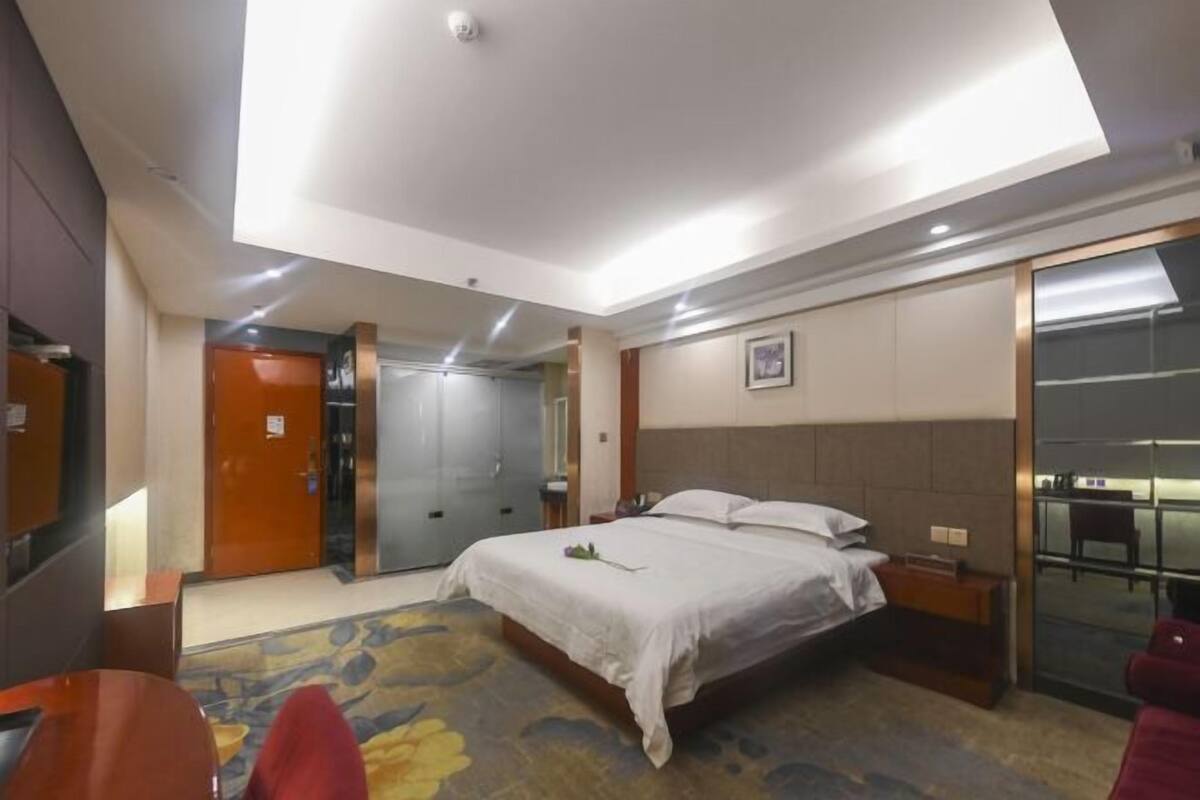 A hotel room with a bed, a desk, a chair, a wardrobe, and a bathroom door.