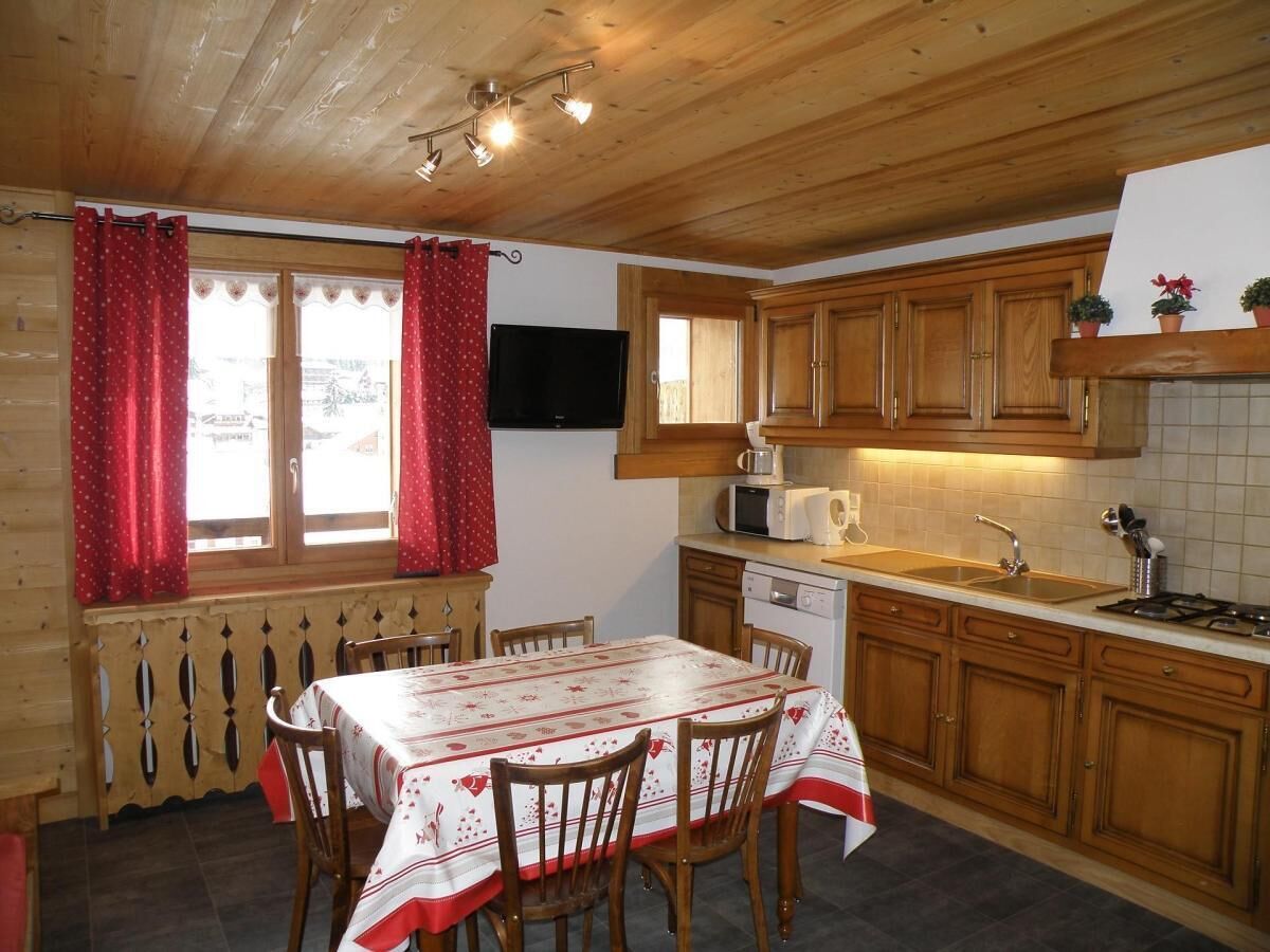 A wooden cabin-style kitchen with a dining table and chairs, wooden cabinets, a microwave, and a sink.