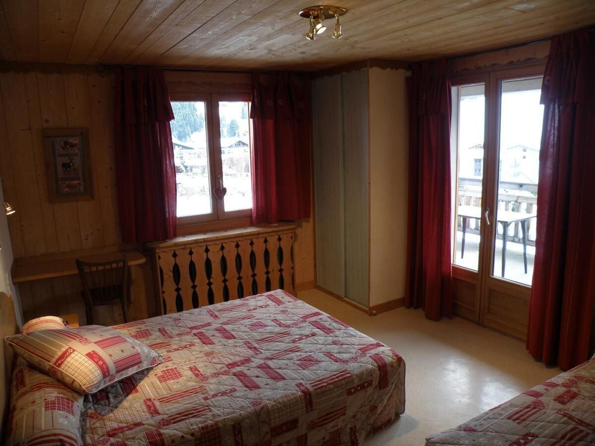 A cozy room with a bed, a desk, and a window with curtains.