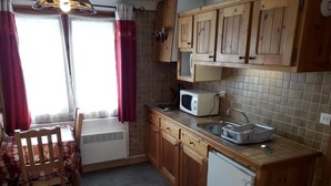 A compact kitchen with wooden cabinets, a microwave, a sink, and a small refrigerator. - Wifi, Ground floor, parking, tv, ski locker, 15m², Les Gets (Les Gets)