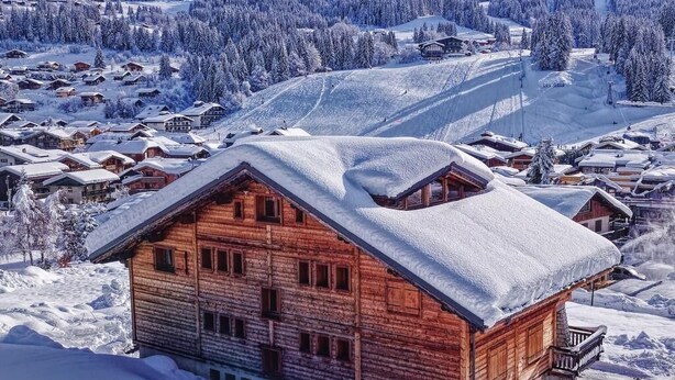 A wooden chalet with a balcony, surrounded by snow-covered trees and a ski slope in the background. - Wifi, Ground floor, parking, tv, ski locker, 15m², Les Gets (Les Gets)