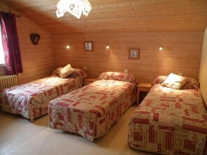 A room with three beds, each with a quilted cover, wooden walls, and a ceiling light fixture. - Wifi, 350m from ski lifts, 2nd floor, balcony, parking, tv, ski locker, 62m², Les Gets (Les Gets)