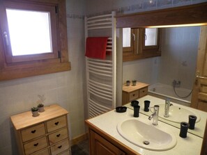 A bathroom with a wooden vanity, a sink, a mirror, a towel rack, a window, and a bathtub. - Wifi, 350m from ski lifts, 1st floor, parking, tv, ski locker, 52m², Les Gets (Les Gets)