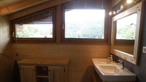 Un baño de cabaña de madera con dos lavamanos, un tocador y un ventanal grande.