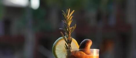 En cocktail i ett vinglas, garnerad med en citronskiva och en kvist rosmarin, placerad på ett bord vid poolen.