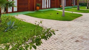 Un resort con cabine a tetto di paglia, un vialetto lastricato e vegetazione lussureggiante.