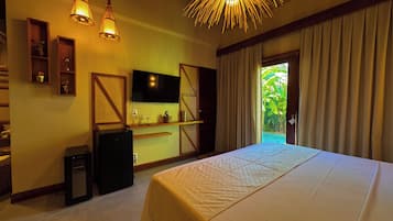 A hotel room with a bed, a television, a desk, and a view of greenery outside.