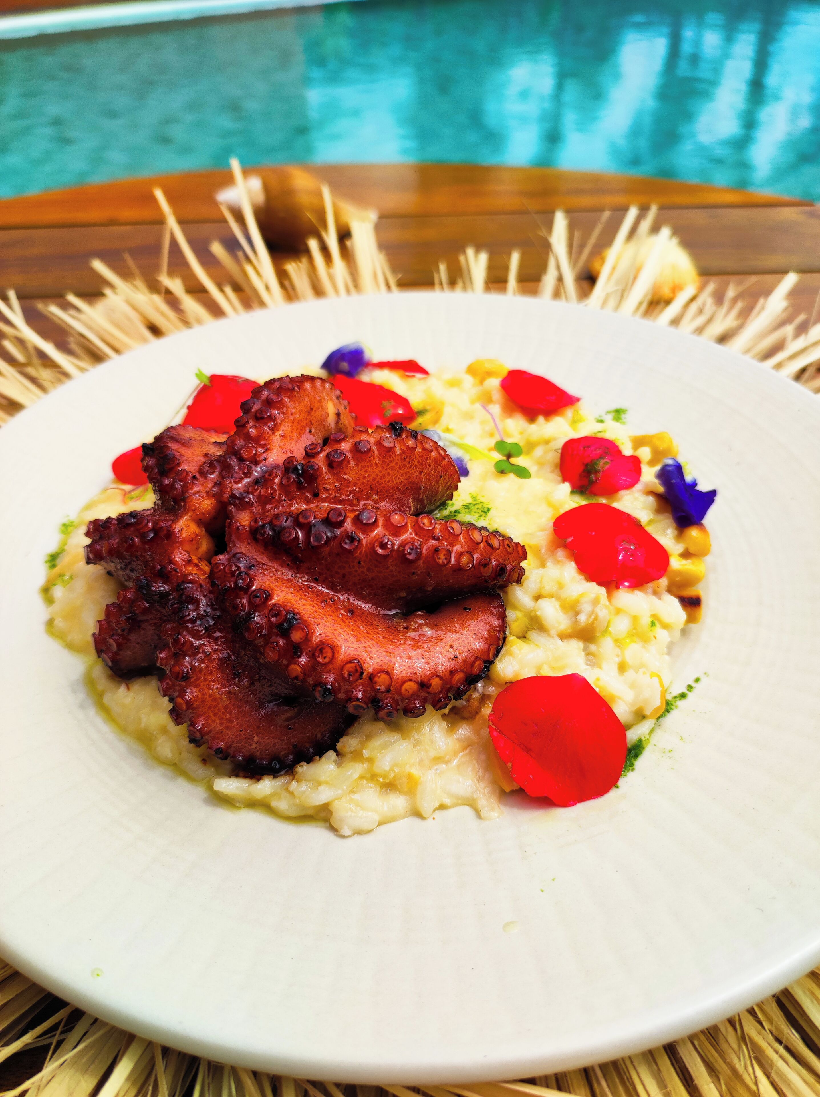 A plate of food with octopus and vegetables on a white plate.