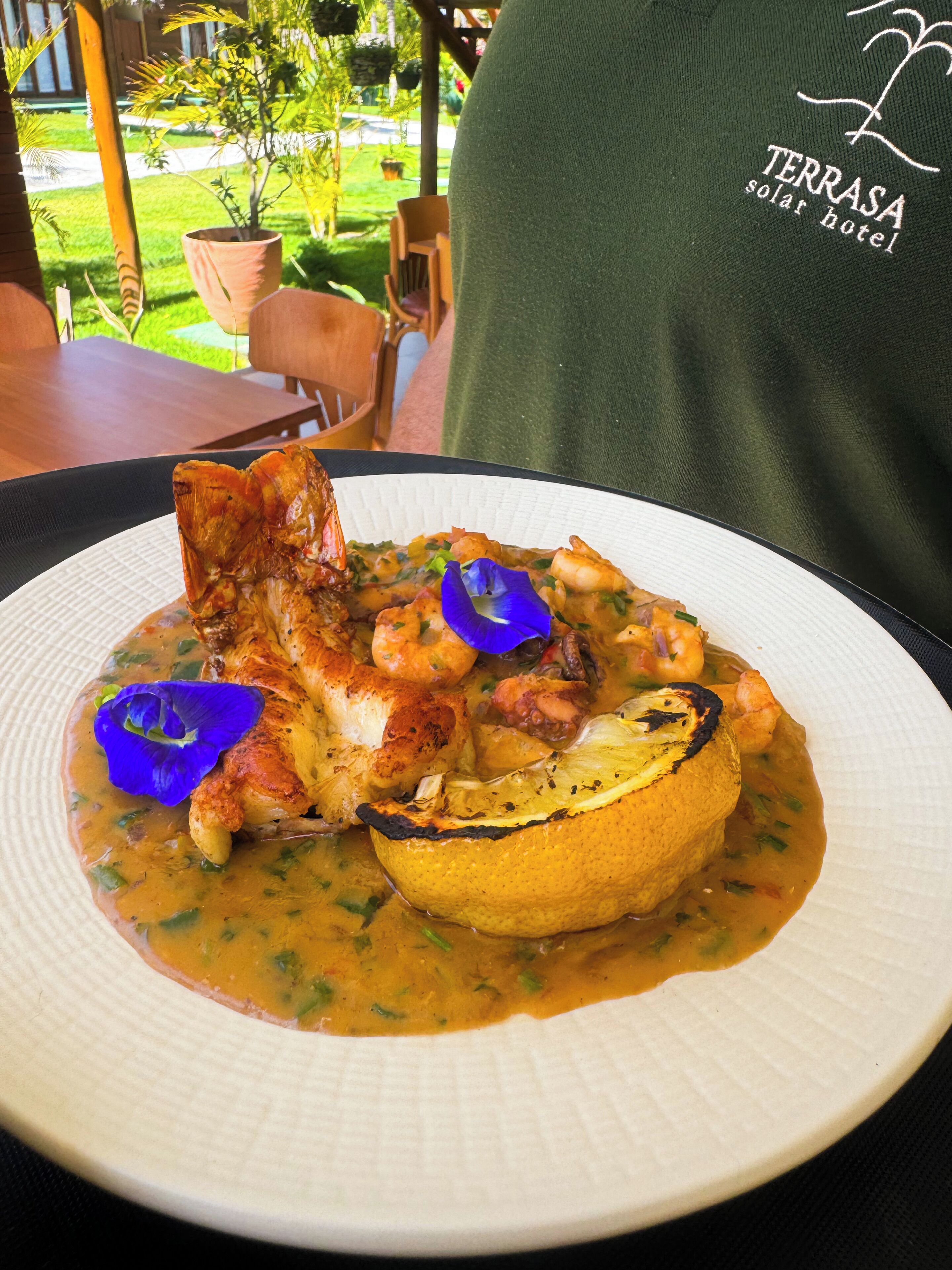A plate of food with shrimp, chicken, and a lemon slice, served on a white plate.