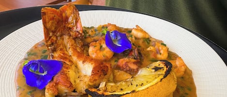 A plate of food with shrimp, chicken, and a lemon slice, served on a white plate.