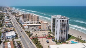 A coastal hotel with a pool, beachfront view, and a parking lot.
