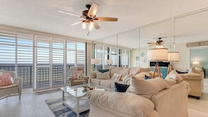 A spacious living room with a large sofa set, a coffee table, and a ceiling fan.