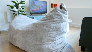 A large, plush bean bag chair in a living room with a flat-screen TV, a plant, and a small table. - Central Trafford Duplex With Shop at Base - Pass the Keys (Manchester)