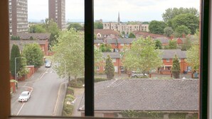 A residential area with a road, houses, and a tall building in the background. - Central Trafford Duplex With Shop at Base - Pass the Keys (Manchester)