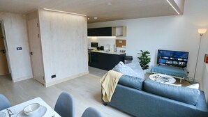 A modern living room with a sofa, dining table, and a TV. - Central Trafford Duplex With Shop at Base - Pass the Keys (Manchester)