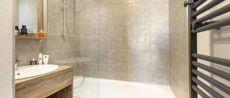 Een moderne badkamer met een douche, wastafel en badkamermeubel.