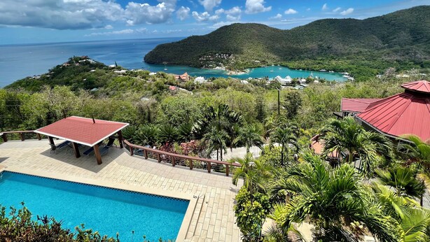 Ein Resort mit Schwimmbad, üppiger Vegetation und Blick auf den Ozean und die Hügel.