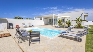 A modern outdoor pool area with lounge chairs, a barbecue, and a covered patio. - Villa Andromeda by Villa Plus (Santa Maria del Focallo)