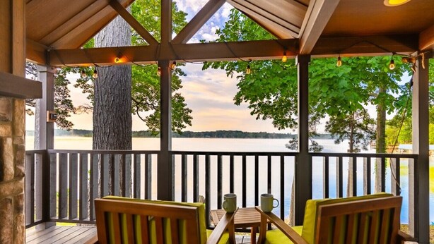 Un espace extérieur abrité, aménagé pour s’asseoir, avec vue sur un lac.