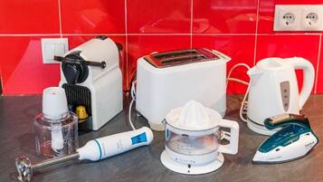 A kitchen counter with a toaster, a kettle, a juicer, an iron, and a bottle of hand soap.