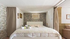 A neatly arranged bedroom with a bed, a nightstand, a wall-mounted shelf, and a window with a curtain.