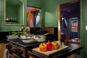 A kitchen with a stove, pots, and fresh bell peppers on the counter.