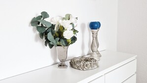 A white console table with a framed world map, a vase with white flowers, and a blue decorative item. - Weser Pension - Zweibettzimmer mit Eigenem Bad Nr. 1 (Brake (Unterweser))