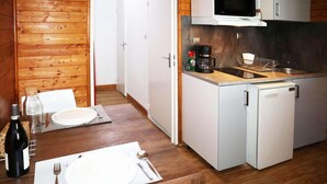 A compact kitchen with a refrigerator, microwave, and coffee maker. A dining table with plates and cutlery is set up. - 100m from ski slopes, 1st floor, view valley, tv, ski locker, 20m², Les Orres (Les Orres)