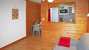 A cozy room with wooden walls, a dining area with a table and chairs, and a kitchenette with a microwave. - 100m from ski slopes, 1st floor, view valley, tv, ski locker, 20m², Les Orres (Les Orres)