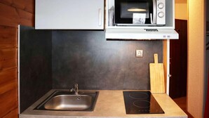A compact kitchen with a sink, a microwave, and an induction cooktop. - 100m from resort center, 1st floor, view valley, tv, ski locker, 20m², Les Orres (Les Orres)