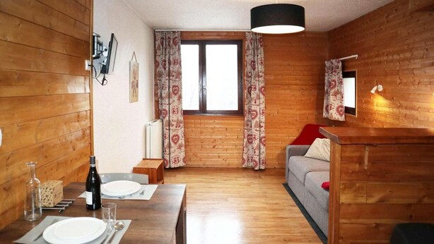 A wooden interior with a dining area, a sofa, and a window with patterned curtains. - 100m from resort center, 1st floor, view valley, tv, ski locker, 20m², Les Orres (Les Orres)