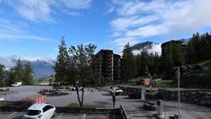 A parking lot with several cars, a small building, and a mountainous backdrop. - 100m from resort center, 1st floor, view valley, tv, ski locker, 20m², Les Orres (Les Orres)