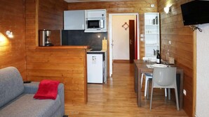 A compact living space with a kitchenette, a dining area, and a sofa with a red throw. - 100m from resort center, 1st floor, view valley, tv, ski locker, 20m², Les Orres (Les Orres)