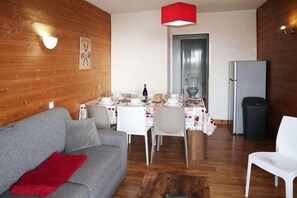 A compact living space with a dining area, a sofa, and a refrigerator.