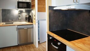 Cocina compacta equipada con lavavajillas, microondas, cafetera y estufa.