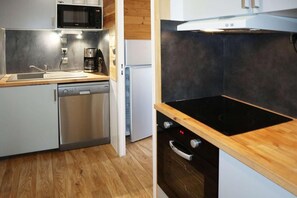 A compact kitchen with a dishwasher, microwave, coffee maker, and a stove.