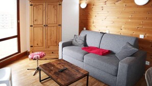 Una sala de estar con un sofá gris, un armario de madera y una mesa de centro de madera.