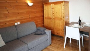 Une pièce chaleureuse avec un canapé gris, des meubles en bois et une table à manger dressée pour deux personnes.
