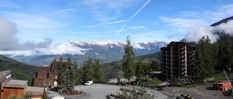 A mountainous town with a parking area, buildings, and a view of snow-capped peaks.